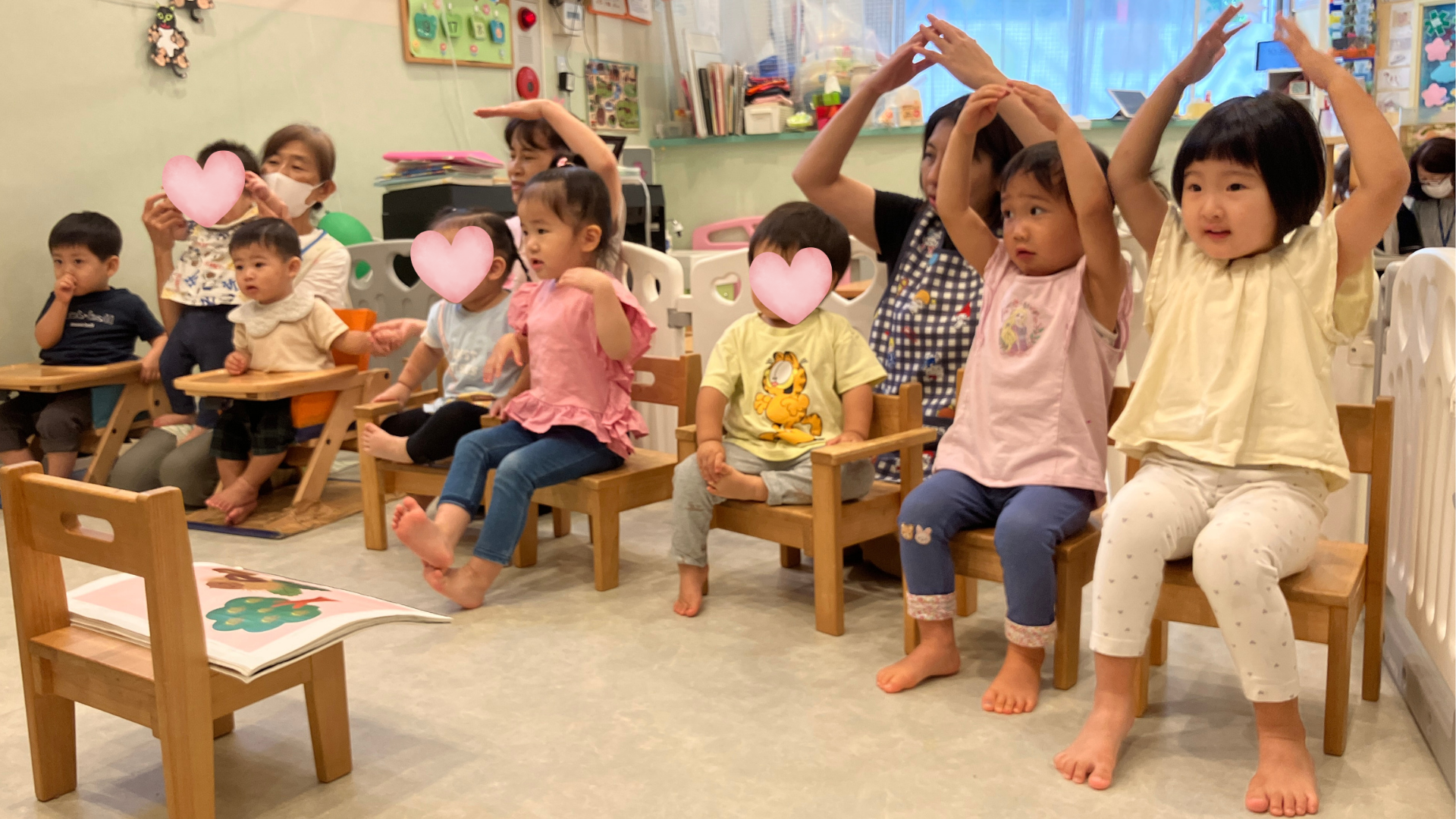 真帆お姉さんと音楽に合わせて手を上げる子供たち
